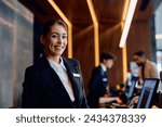 Happy female receptionist working at hotel front desk and looking at camera. 