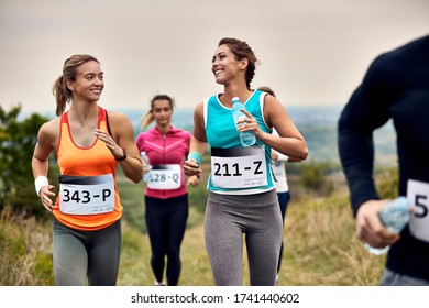 Happy Female Runners Talking While Running Marathon In Nature. 