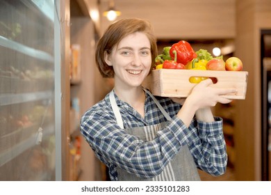 Happy female shopkeeper arranging or preparing a fruits and vegetables on a shelf in supermarket. Female supermarket staff preparing food and vegetable on a shelf. - Powered by Shutterstock