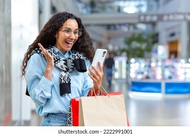 Happy Female Shopper Inside Store Talking On Video Call With Friends, Hispanic Woman Using Smartphone For Online Remote Communication, Sharing Information About Sales And Discounts.