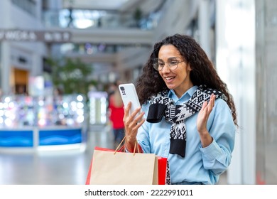 Happy Female Shopper Inside Store Talking On Video Call With Friends, Hispanic Woman Using Smartphone For Online Remote Communication, Sharing Information About Sales And Discounts.