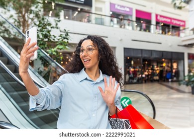 Happy Female Shopper Inside Store Talking On Video Call With Friends, Hispanic Woman Using Smartphone For Online Remote Communication, Sharing Information About Sales And Discounts.