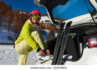 Happy Female Skier Putting On Her Ski Boots