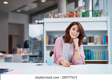 Happy Female Small Business Owner Sitting At Big Desk