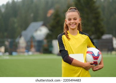 A happy female soccer player on the field a portrait of a smiling football teenage girl with a soccer ball in her hand. - Powered by Shutterstock