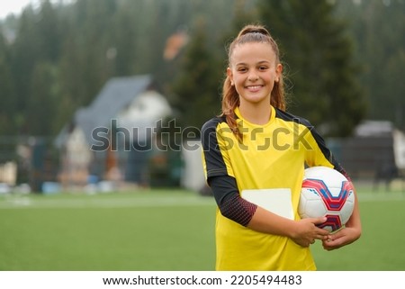 A happy female soccer player on the field a portrait of a smiling football teenage girl with a soccer ball in her hand.