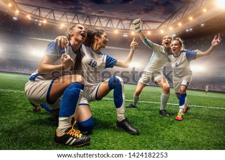Happy Female Soccer players on a professional soccer stadium. Girls Team emotionally celebrates victory