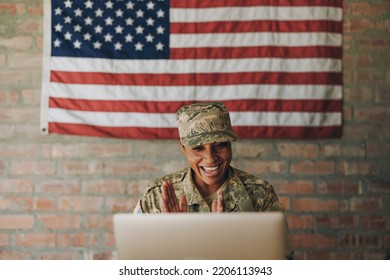 Happy female soldier smiling cheerfully while video calling her family on a laptop. American servicewoman communicating with her loved ones while serving her country in the army. - Powered by Shutterstock