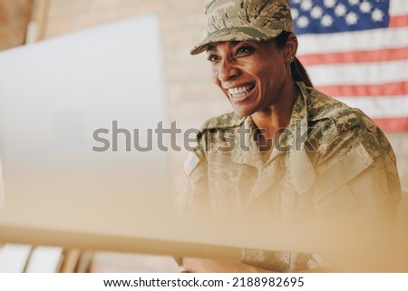 Happy female soldier smiling cheerfully while video chatting with her family on a laptop. American servicewoman communicating with her loved ones while serving her country in the army.