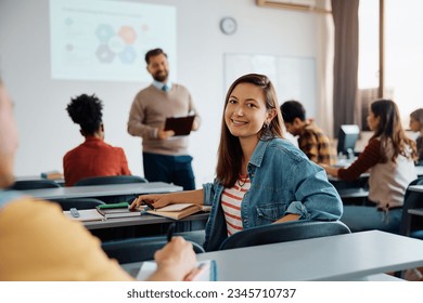 Happy female student attending a class at the university and looking at camera.