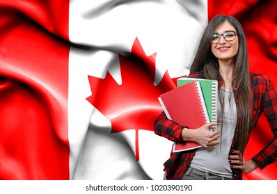 Happy Female Student Holdimg Books Against National Flag Of Canada