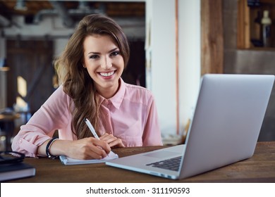 Happy Female Student Learning With Laptop At Cafe