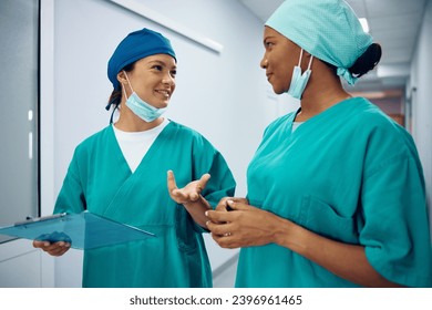 Happy female surgeons talking in a hallway at medical clinic. - Powered by Shutterstock