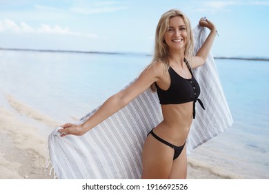 Happy female tourist running on sandy tropical beach, laughing and enjoying summer vacation at carribean resort. Beautiful woman in bikini having fun at seashore.