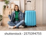 Happy female tourist with suitcase sitting near door in hallway