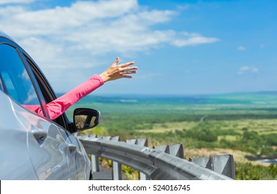 Happy Female Traveler With Her Hand Out Of Car Window Feeling Free. Road Trip And On The Road Concept. (Location Hawaii)