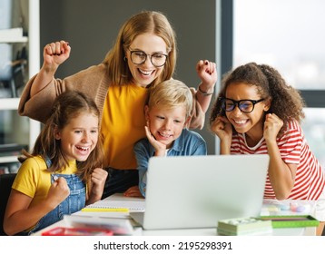 Happy Female Tutor And Group Of Schoolchildren Smiling And   Looking At Laptop Screen During Celebrate Together  Successful Completion Of Collective School Work In A Light Classroom  