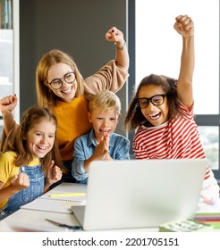 Happy Female Tutor And Group Of Schoolchildren Smiling And   Looking At Laptop Screen During Celebrate Together  Successful Completion Of Collective School Work In A Light Classroom  