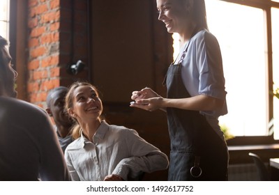 Happy Female Waitress Holding Notepad Taking Order Serving Clients In Cafe Pub Restaurant, Polite Serving Staff Worker Talking To Guests Diverse Friends Group Choose Food And Drinks, Customer Service