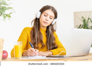 Happy Female In Wireless Headphones Studying Online Course, Using Pc And Writing In Notepad, Copy Space. Gig Economy, Digital Nomad, Distance Education. Side View Of Mature Woman Work From Home