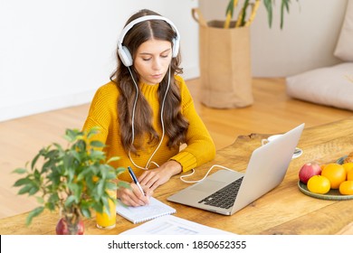 Happy Female In Wireless Headphones Studying Online Course, Using Pc And Writing In Notepad, Copy Space. Gig Economy, Digital Nomad, Distance Education. Side View Of Mature Woman Work From Home