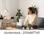 Happy female writer with typewriter, books and cup of tea sitting on sofa at home