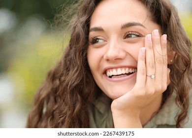 Happy fiencee smiling showing ring at camera in a park - Powered by Shutterstock