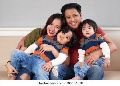 Happy Filipino man hugging his wife and two children
