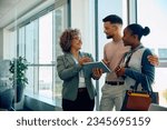 Happy financial advisor using touchpad while talking to young couple during the meeting. Copy space.