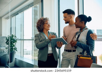 Happy financial advisor using touchpad while talking to young couple during the meeting. Copy space. - Powered by Shutterstock