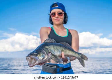 Happy fisher woman with zander walleye fish trophy at the boat