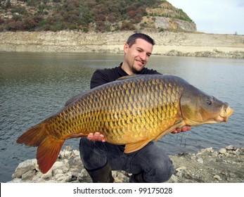 Happy  Fisherman Holding A Giant Common Carp