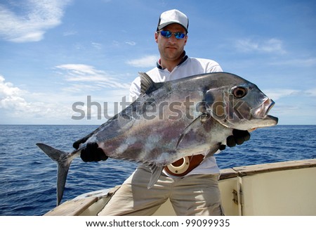 Happy  fisherman holding a trevally jack