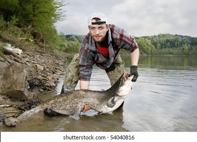 A happy fisherman presenting his fishing trophy caught in a Polish lake - catfish (Silurus glanis)