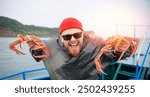 Happy fisherman tourist man holding fresh crabs while fishing on boat in sea, Kamchatka travel.