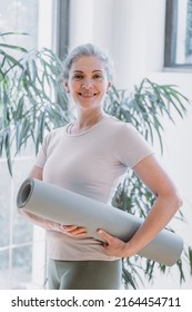 Happy Fit Middle Aged Old Woman Looking At Camera, Holding Yoga Mat, Standing At Home. Seniors Fitness Exercises, Health And Body Care Training. Mature People Active Lifestyle Concept