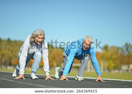 Happy fit senior couple jogging at stadium