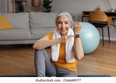 Happy Fit Senior Woman Pointing At Activity Fitness Tracker And Smiling At Camera, Having Break In Her Training At Home. Modern Sports Gadgets, Fitness Equipment Concept