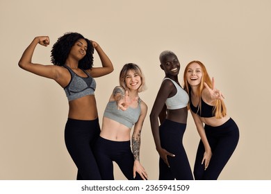 Happy fit sporty diverse different girls group having fun posing at beige background. Multiracial positive young women friends wear sportswear advertising fitness gym yoga body trainings together. - Powered by Shutterstock