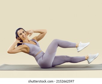 Happy fit woman with beautiful abs enjoying her fitness workout at the gym. Studio shot of a cheerful smiling lady in a crop top and leggings doing bicycle crunches exercise on a sports mat - Shutterstock ID 2152662597