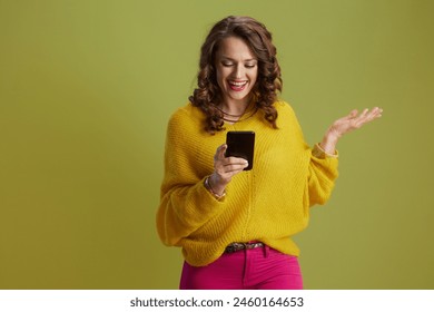 happy fit woman isolated on green in yellow sweater using smartphone. - Powered by Shutterstock