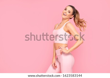 Happy fit Woman Over Pink Studio Background. Smiling girl after Fitness Workout. Healthy lifestyle concept.