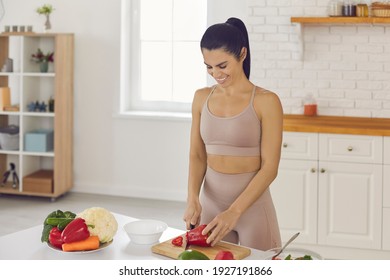 Happy Fit Young Woman Cooking Healthy Vegetarian Food At Home. Smiling Housewife Or Diet Coach Standing At Kitchen Table And Chopping Red Sweet Or Bell Peppers For Vegetable Salad Rich In Vitamins