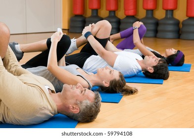 Happy fitness people class in a row doing some aerobic stretching after workout at gym - Powered by Shutterstock