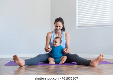 Happy Fitness Woman Doing Yoga Stretching Exercise With Infant Son. Active Mother Playing With Toddler On Floor. Little Boy Enjoying With Mom Sitting On Purple Yoga Mat At Home.