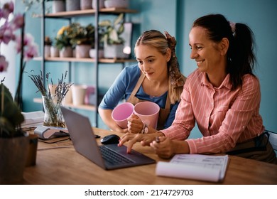 Happy Flower Shop Owner And Her Younger Coworker Checking Online Orders On Laptop While Working At The Store. 