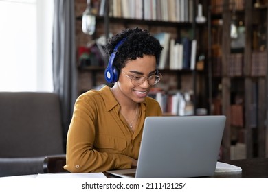 Happy Focused Busy African Female Employee In Headphones Talking To Client On Video Call. Adult College Student Watching Learning Webinar On Internet, Attending Online Studying Virtual Conference