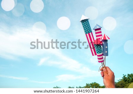 Happy fourth of July. Woman or man hand holding fireworks rockets in national american colors over sunset sky