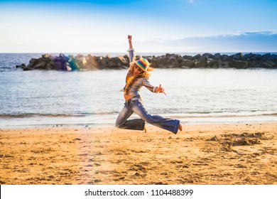 happy freedom crazy middle age woman jump on the beach for happiness and joyfun life outdoor vacation summer ocean and beach concept. fashion hippy clothes and beautiful model over a blue background