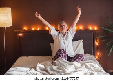 Happy Fresh Mature Middle Aged Woman Stretching In Bed Waking Up Alone Happy Concept, Smiling Old Senior Lady Awake After Healthy Sleep Sitting In Cozy Comfortable Bedroom Interior Enjoy Good Morning
